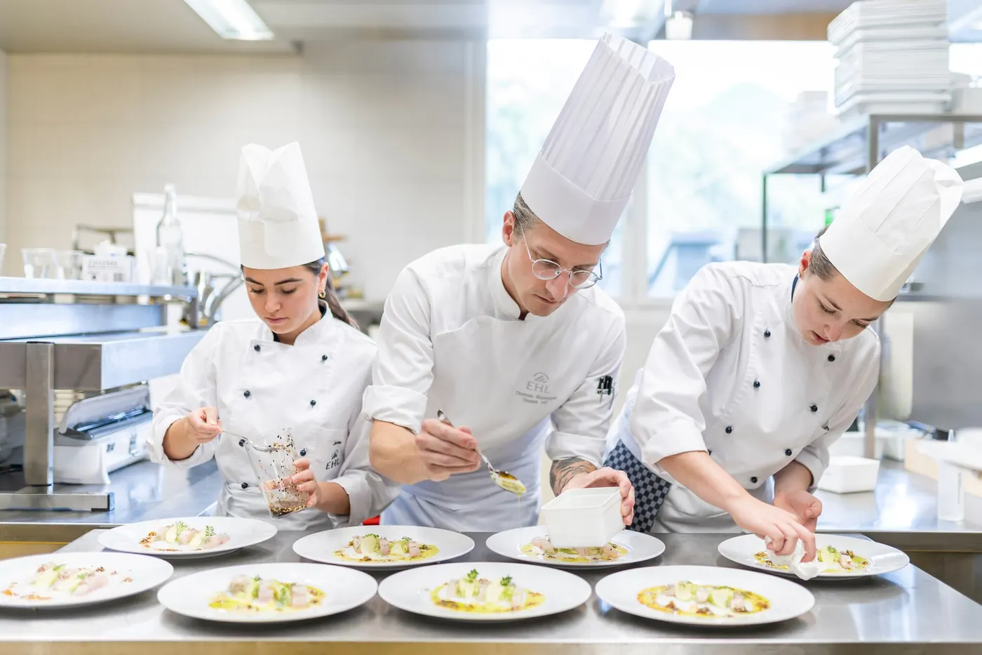 Kitchen trainees working at stainless-steel cooking stations